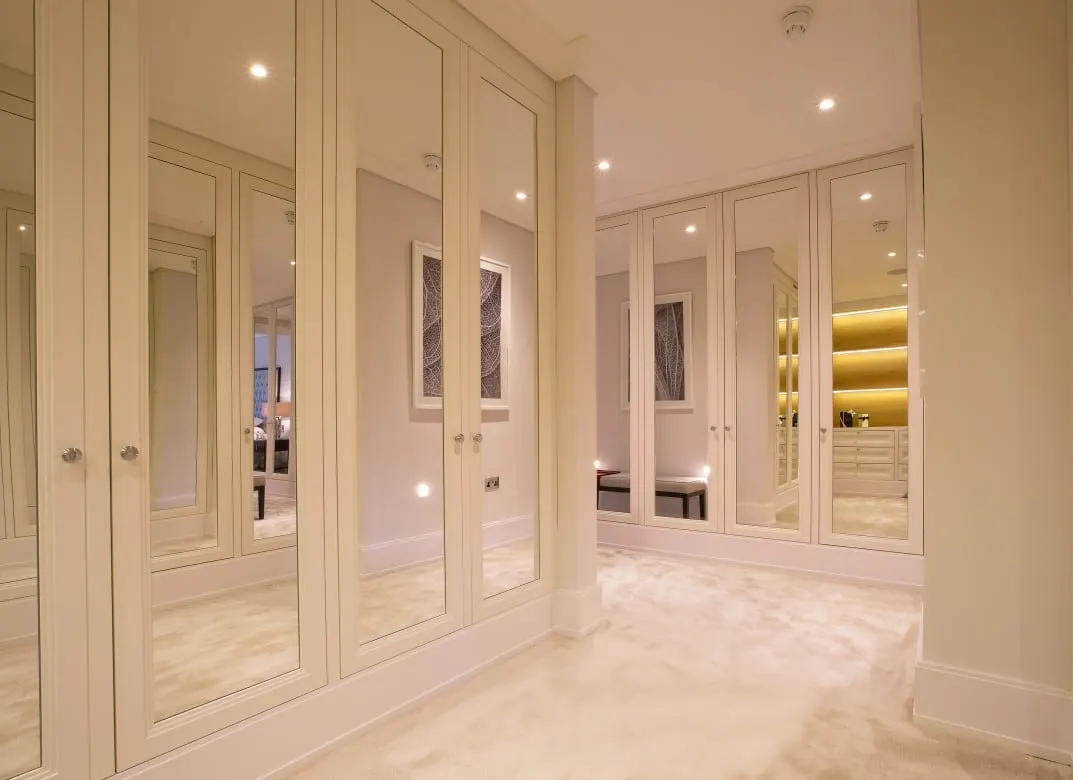 Dressing room lined with cream panelled wardrobes with mirrored doors, Kingston