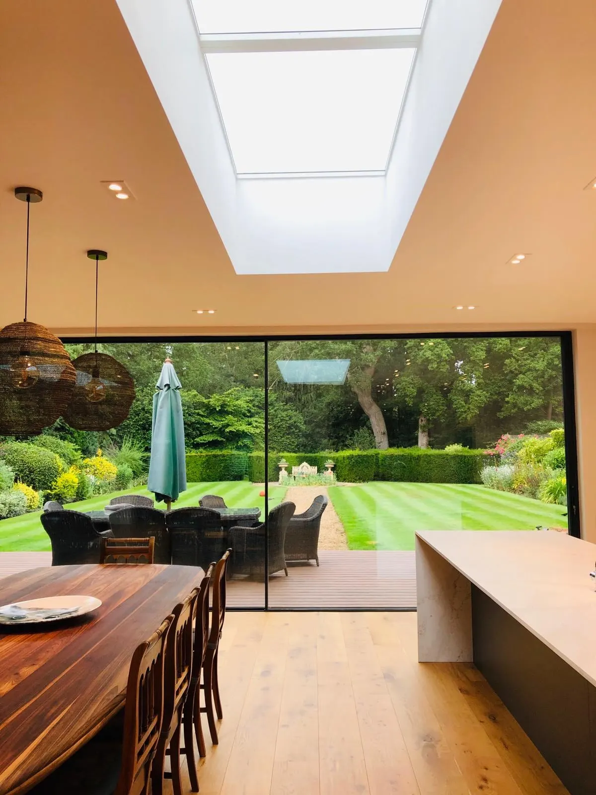 A long roof light over a dining room, with sliding doors open to the garden, West Clandon