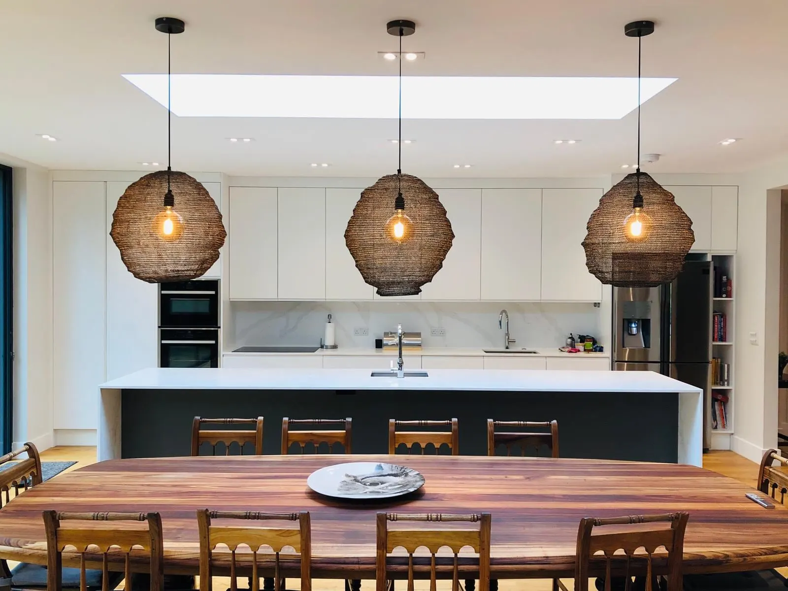 White handleless kitchen with an island under a long roof light, West Clandon