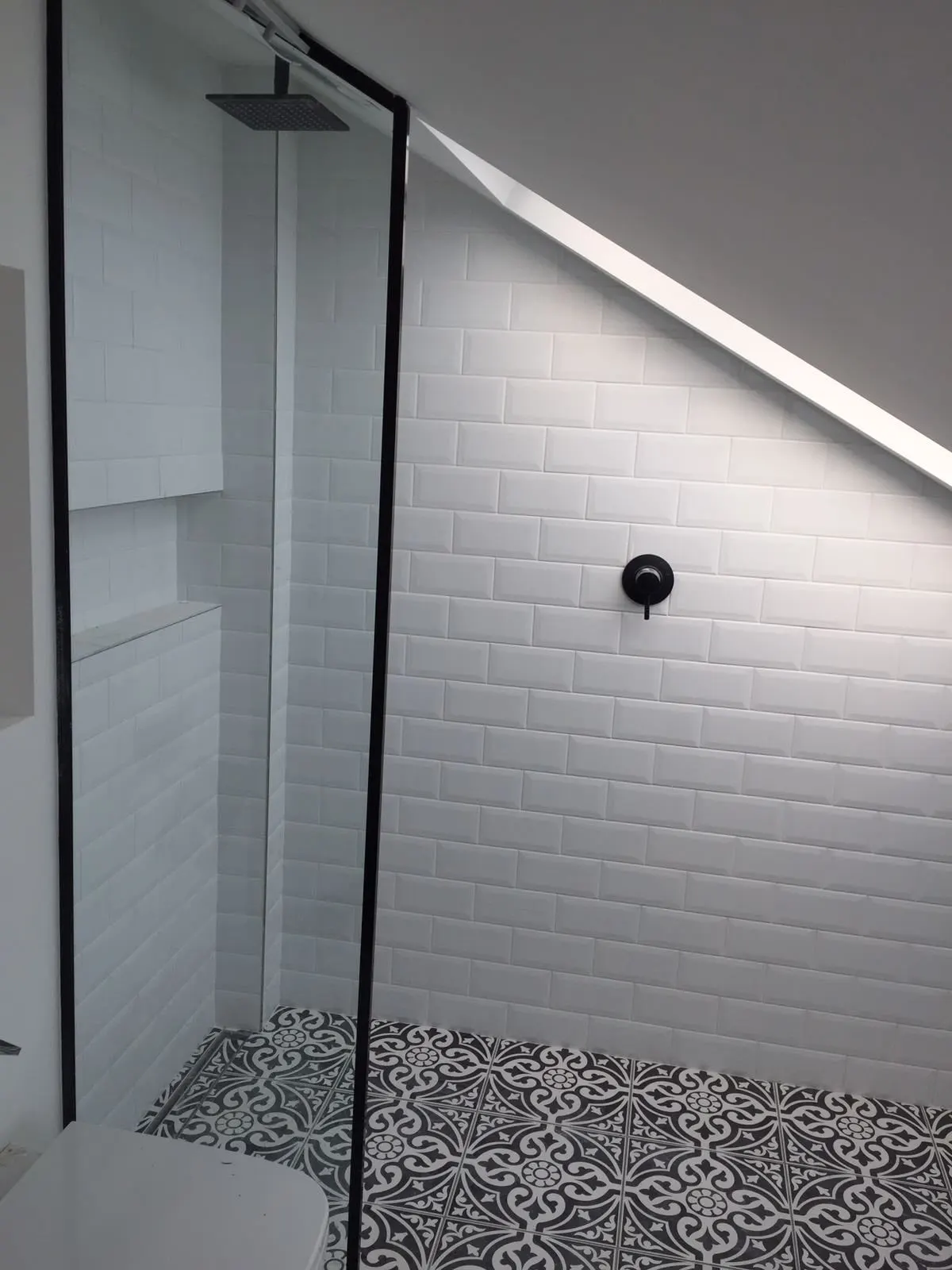 Walk-in shower under the eaves with white metro tiles and a black-framed screen, Fulham