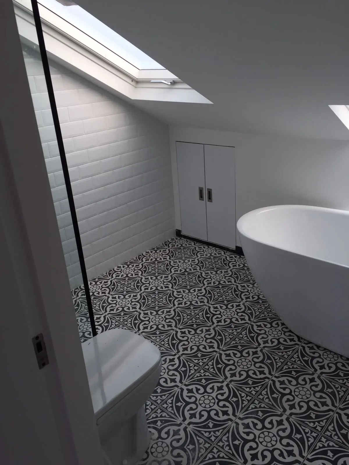 Loft bathroom with a roof light, a freestanding bath and patterned floor tiles, Fulham
