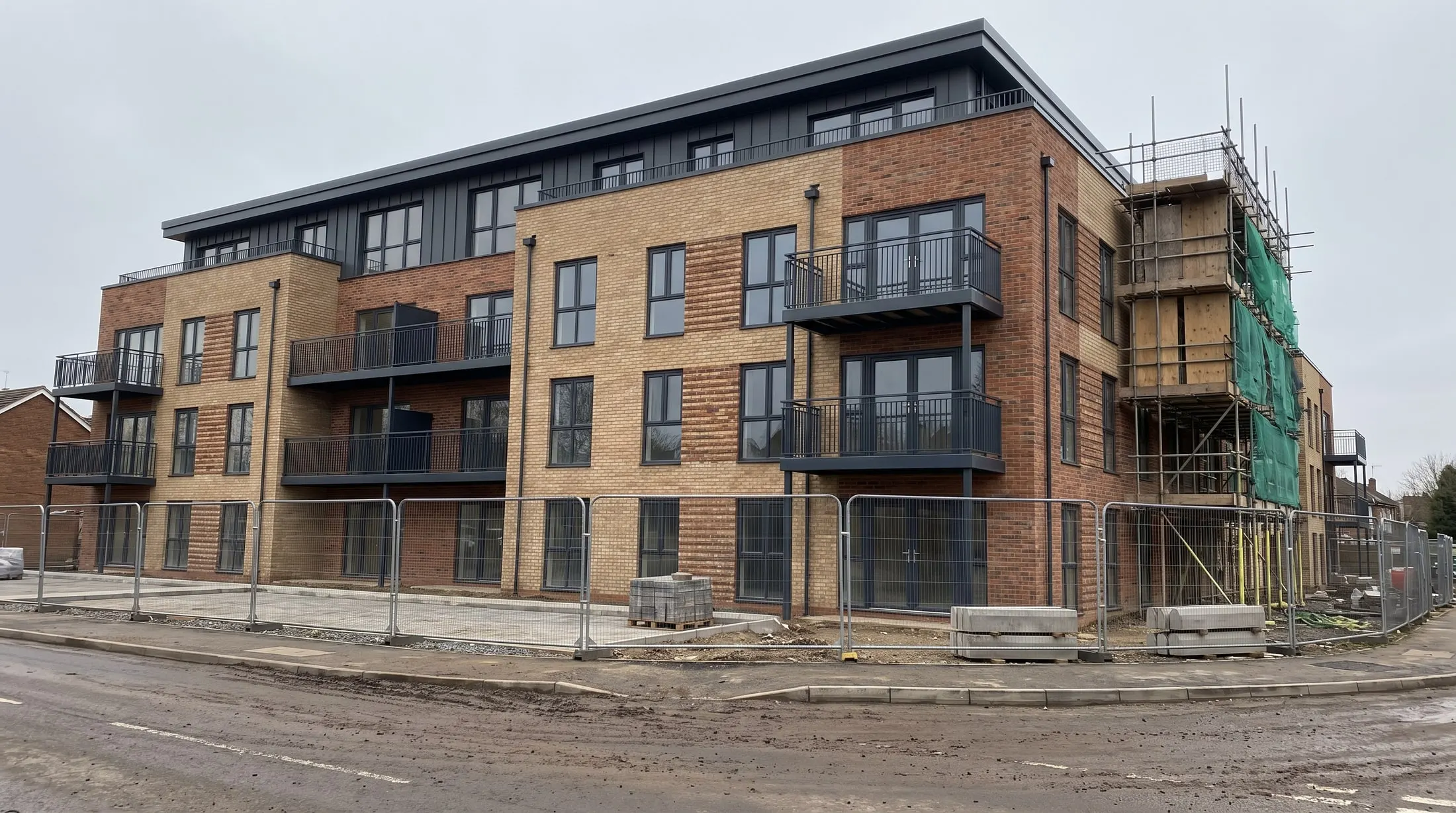 New four-storey brick apartment building nearing completion, scaffolding still up at one end