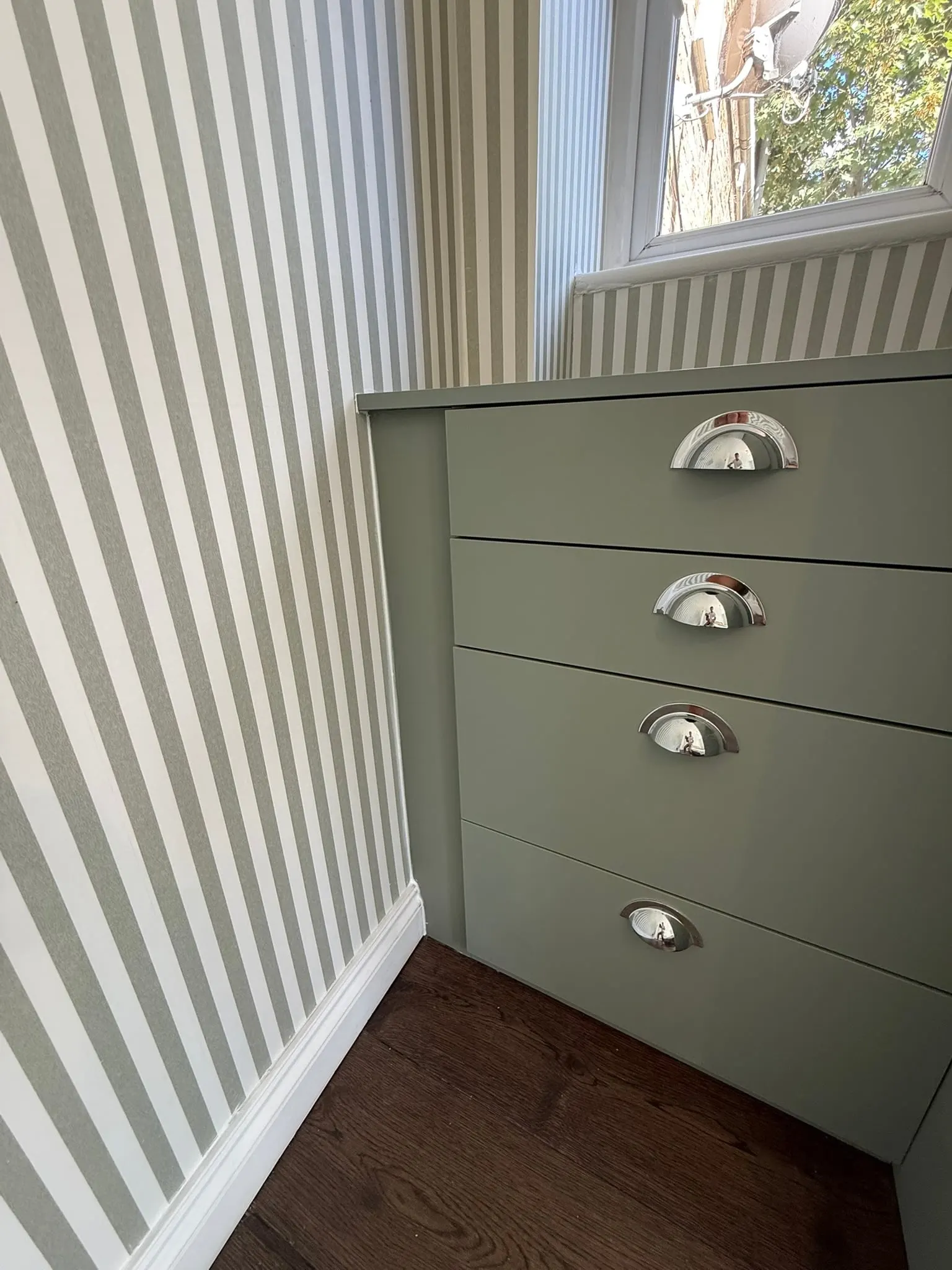 Sage-green built-in drawers with cup handles in an alcove, Islington