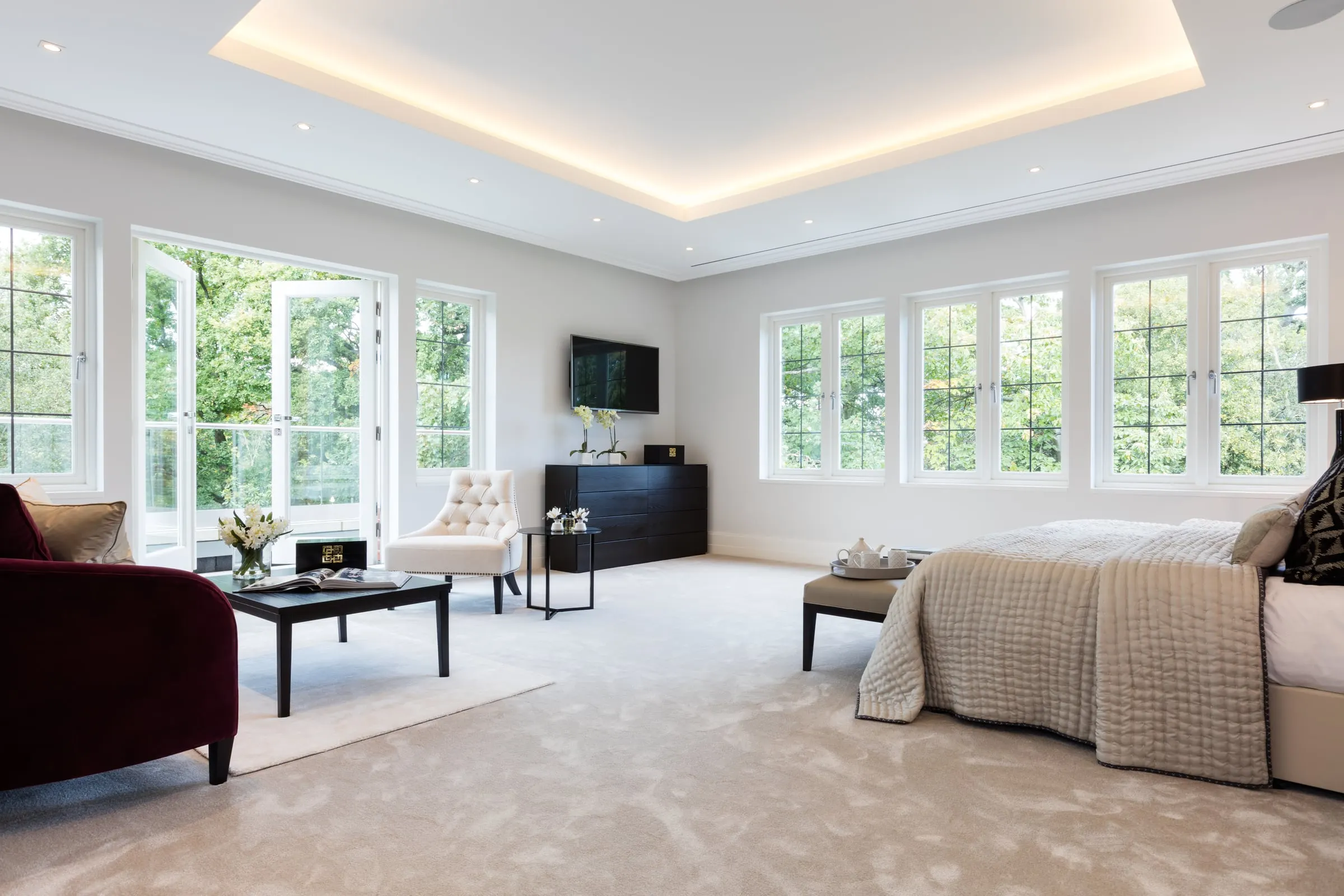 Finished bedroom suite with a seating area and tall windows on two sides