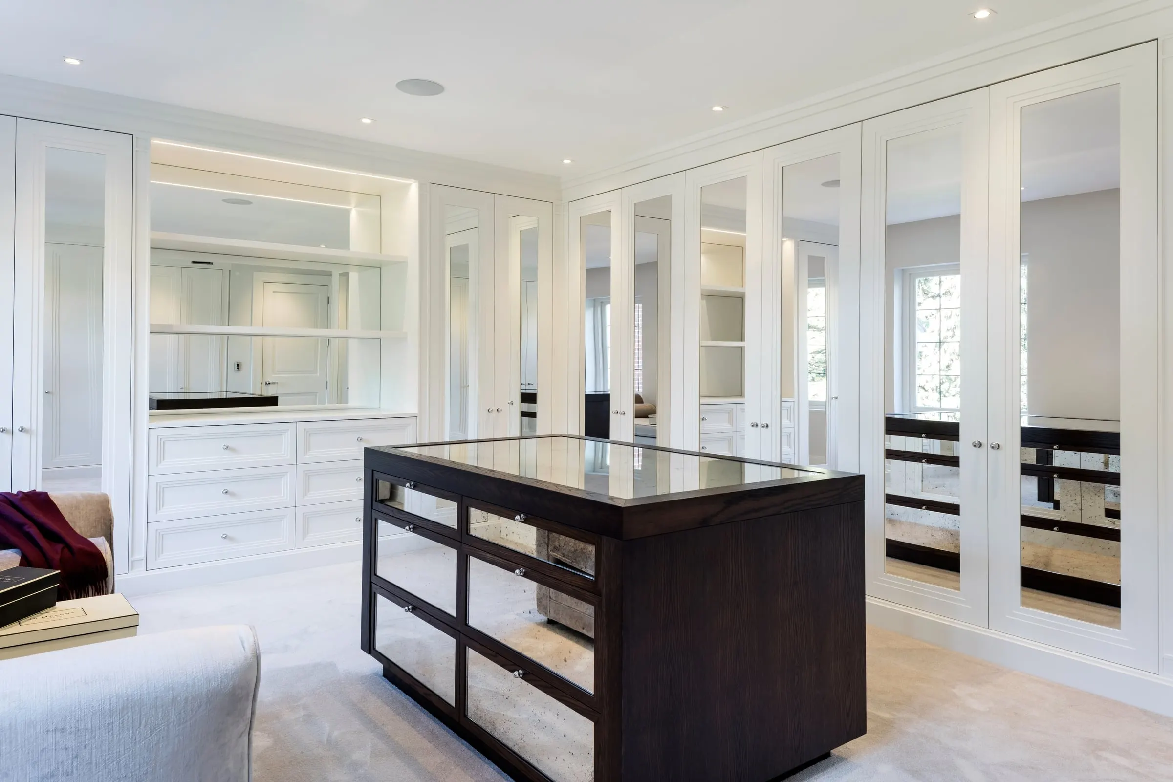 Dressing room with white panelled wardrobes and a dark timber island