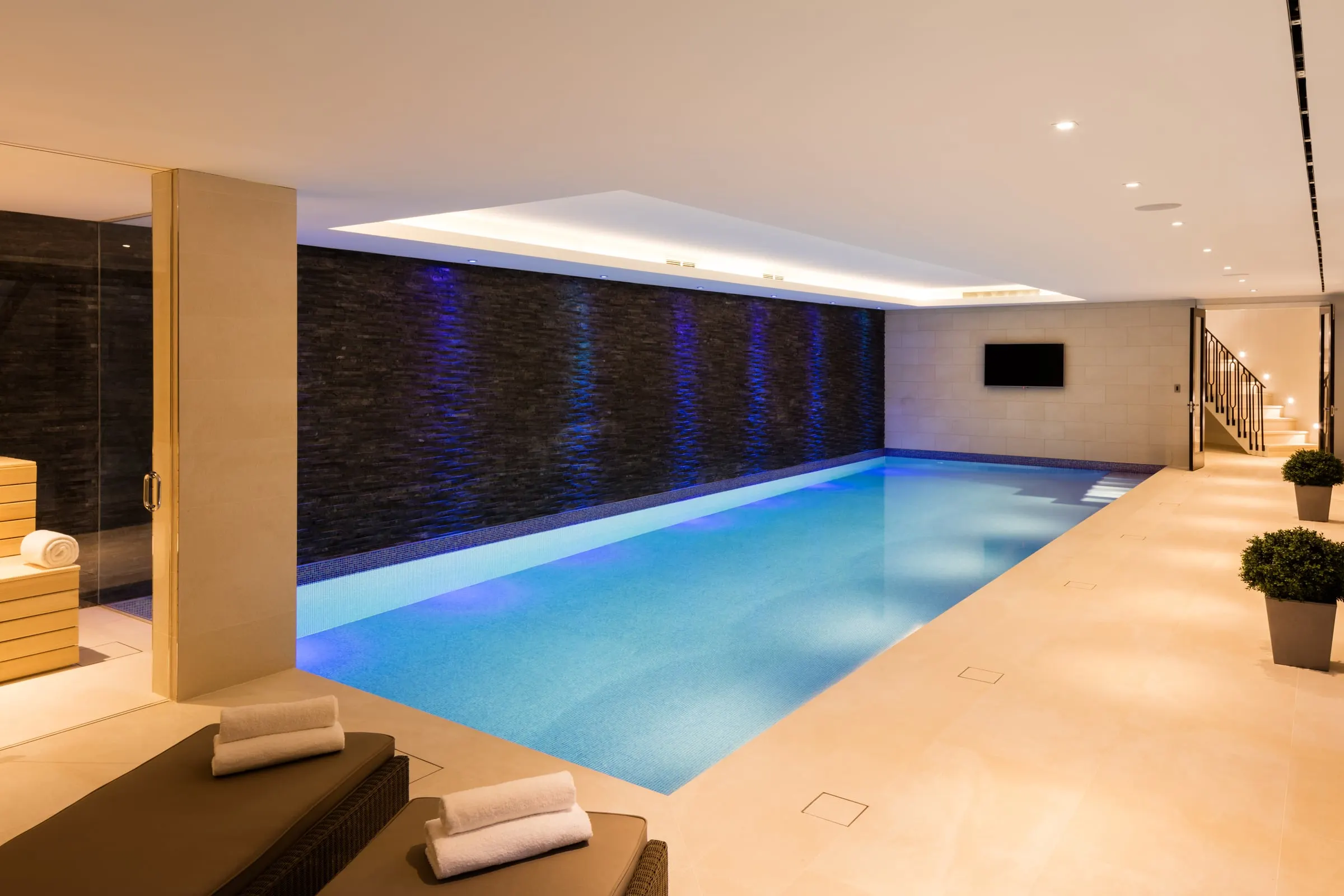 Indoor pool from the seating end, with loungers and steps into the water