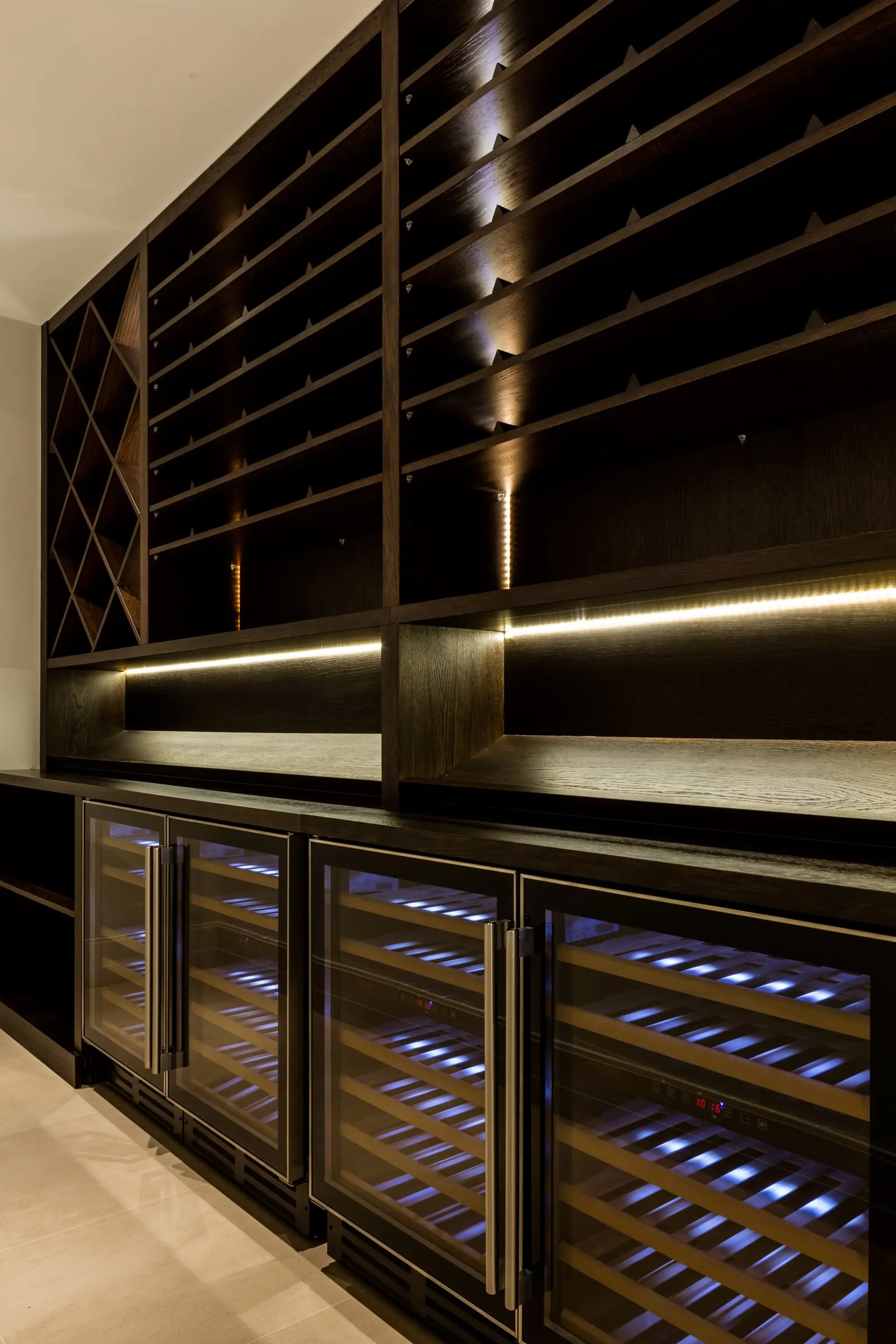 Wine wall in dark timber over a row of built-in wine coolers