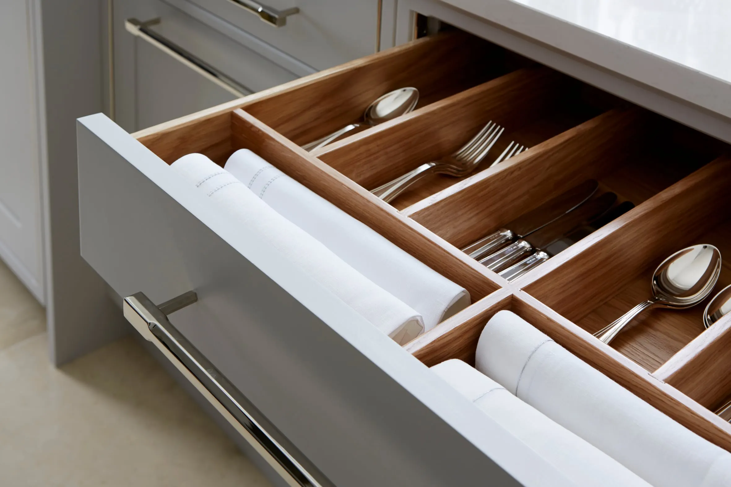 Open cutlery drawer with walnut dividers under a stone worktop