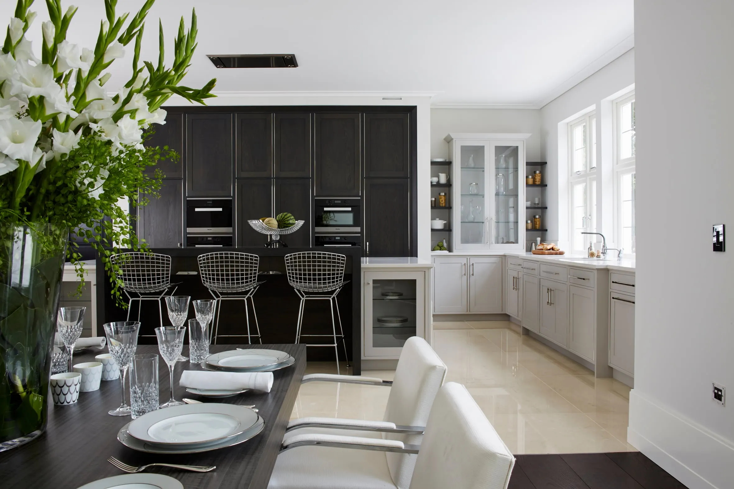 Dining table laid in front of a kitchen of dark oak units and a breakfast bar, Kingston