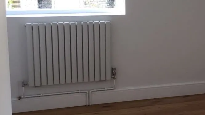 A new column radiator under a window, with its valves and pipework, Fulham
