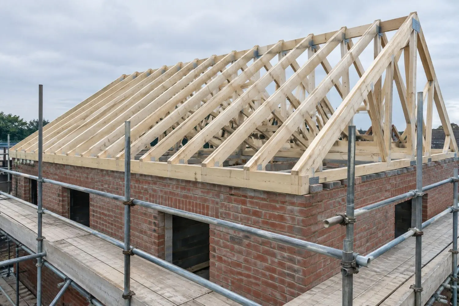 Timber roof structure going up on a brick house, seen from the scaffold
