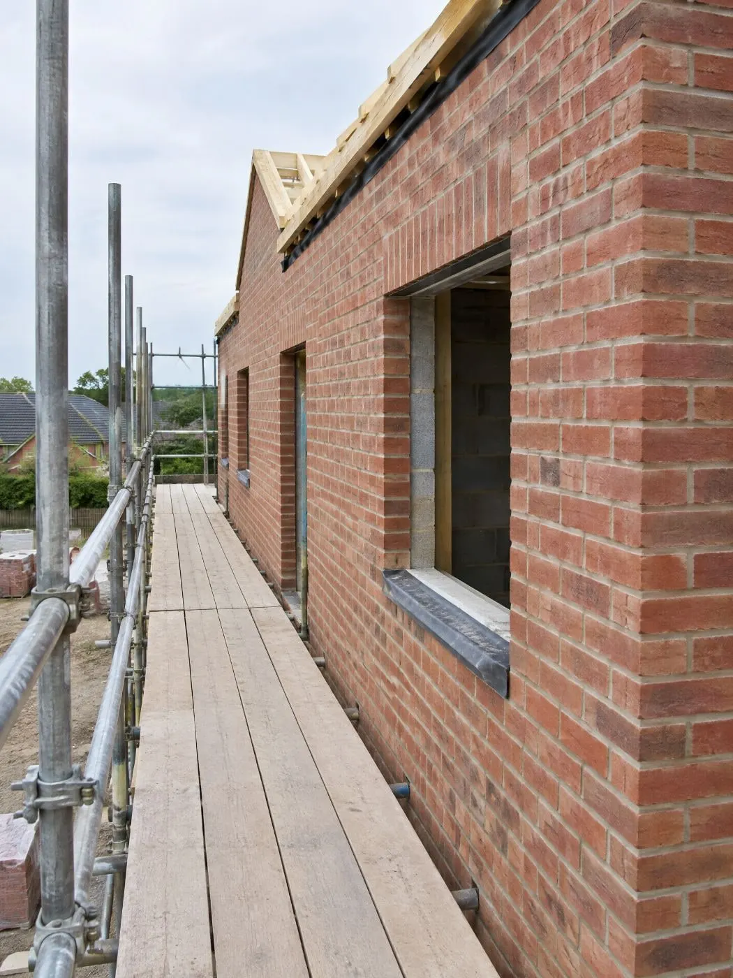 Scaffold walkway along a new brick wall with a window opening