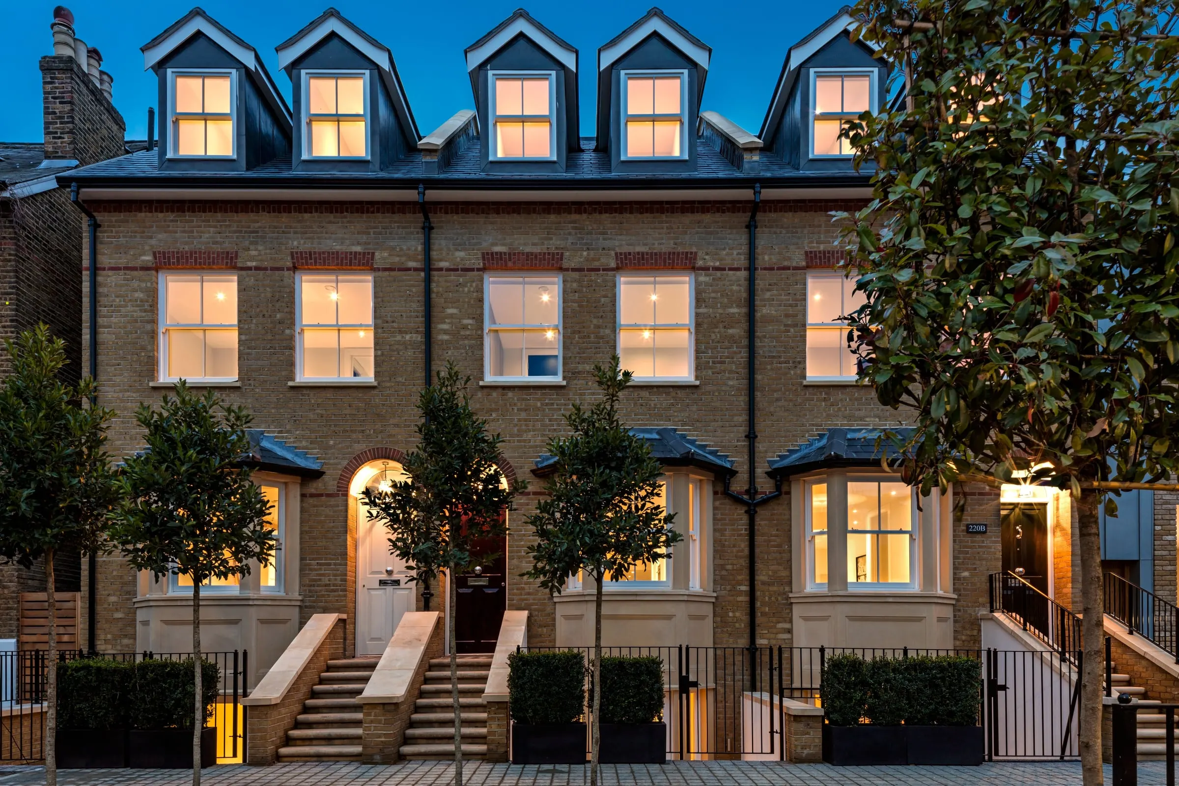 Terrace of new brick town houses at dusk, windows lit, Teddington