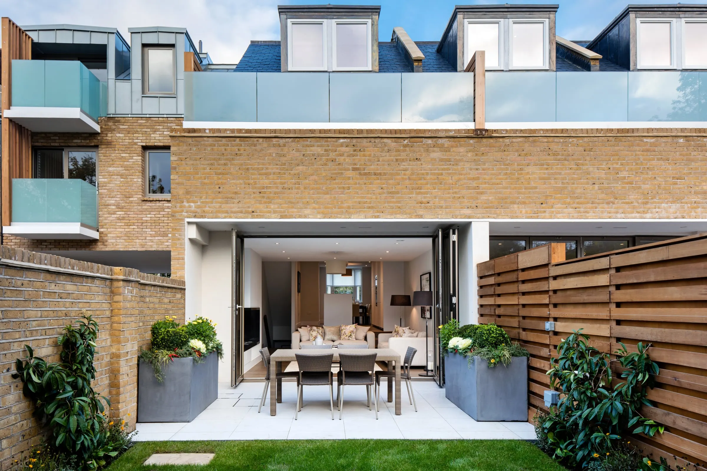 Rear of a town house with bifold doors, a glass-balustraded terrace and zinc dormers, Teddington