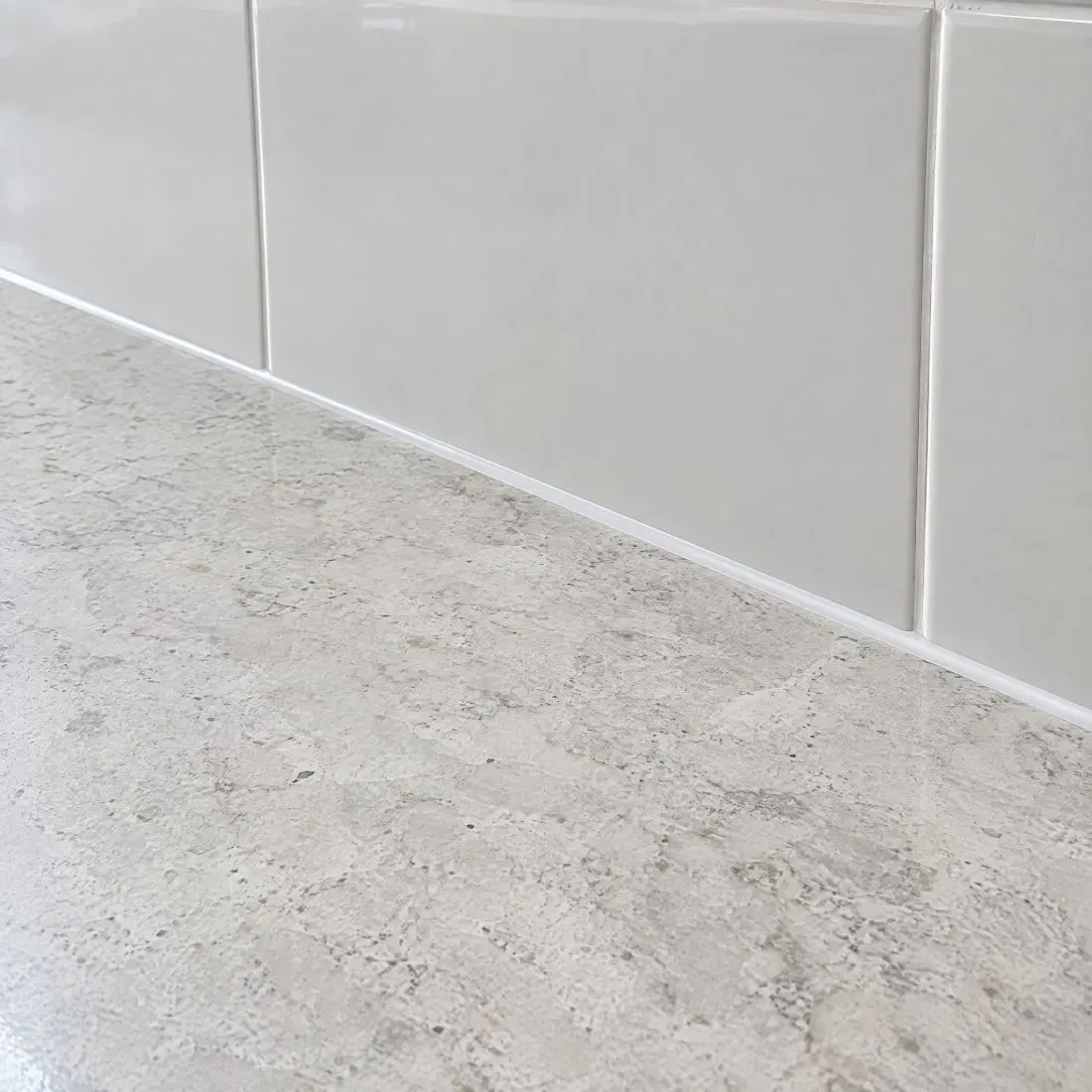 Close view of a stone worktop meeting a tiled upstand